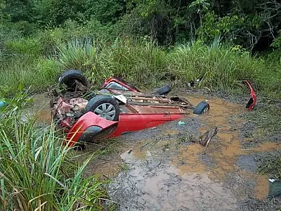 Mulher fica presa em veículo após capotar e cair em açude