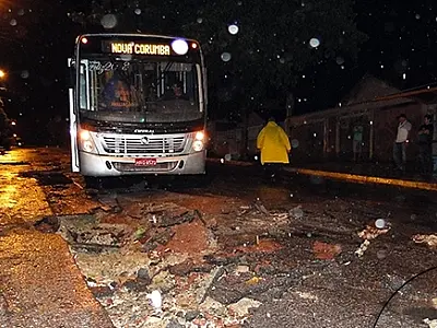 Ônibus cai em buraco aberto em rua pela força da água da chuva